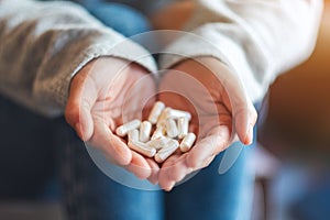 a woman holding white medicine capsules in hands