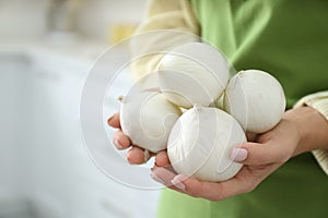 Woman holding white onions indoors