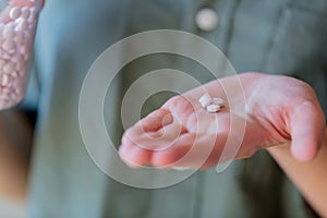 Woman holding a white pills in a hand