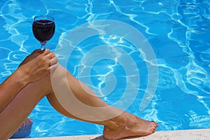 Woman holding wine on her knee at the poolside