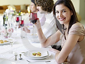 Woman Holding Wineglass With Friends At Dinner Party