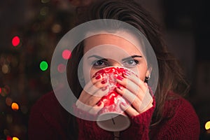 Woman holding winter cup with nice Christmas motive close up on Christmas background. Winter and Christmas time concept.