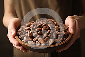 Woman holding wooden bowl of cocoa beans