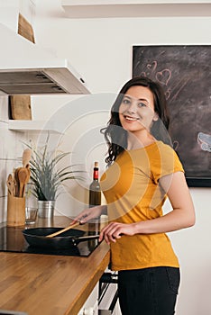 Woman holding wooden spatula near frying