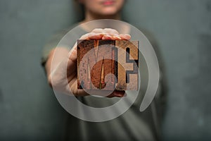 Woman holding the word `me` made of wooden typographic letters