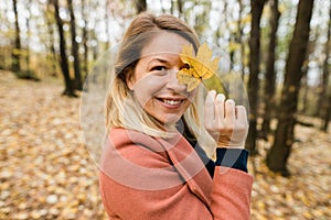 Woman holding yellow autumn leaves in the forest