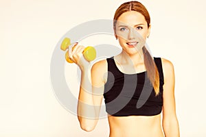 A woman holding a yellow dumbbell. Engaged in fitness