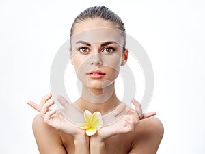 woman holding a yellow flower in her hands clean skin cosmetology naked shoulders
