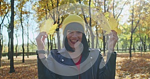 Woman holding yellow maple leaves in autumn park. Close-up lifestyle portrait with natural light. Autumn season and