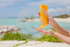 Woman holding yellow sunscreen bottle in hands