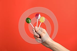 Woman holding yummy candies on color background