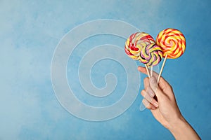 Woman holding yummy candies on color background.