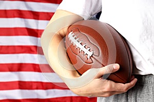 Woman holds American football ball on American flag background