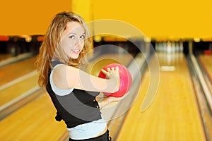 Woman holds ball and prepares to throw in bowling