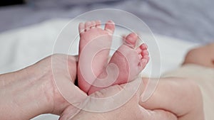 Woman holds bare feet of newborn baby making shape of heart