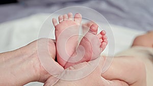Woman holds bare feet of newborn baby making shape of heart
