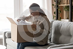 Woman holds big carton box on laps unpack delivered goods