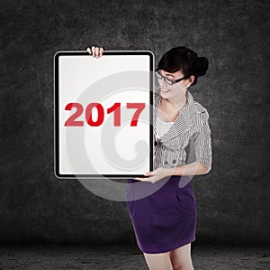 Woman holds billboard with number 2017