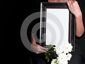 Woman holds blank mourning frame, with flower