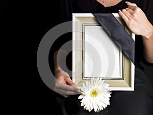 Woman holds blank mourning frame, with flower