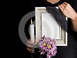 Woman holds blank mourning frame, with flower