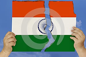 Woman holds in both hands against a blue sky torn in two cardboard with seared edges depicting the national flag, the concept of