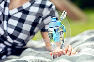 Woman holds the bottle of filtered water outdoors