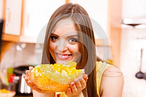 Woman holds bowl full of sliced orange fruits