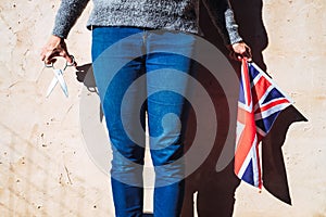 Woman holds with a British flag next to scissors, angered by English politicians