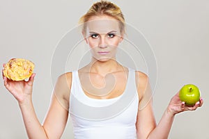 Woman holds cake and fruit in hand choosing