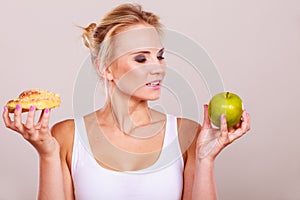 Woman holds cake and fruit in hand choosing