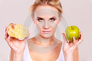 Woman holds cake and fruit in hand choosing