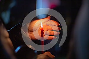 A woman holds a candle in her hand, covering the flame from the wind with her palm, in memory of the dead, killed, dead, deceased