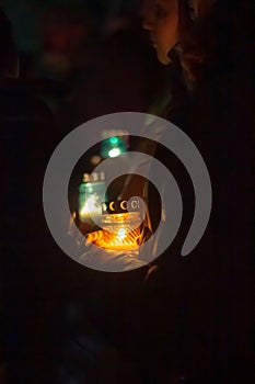 A woman holds a candle in her hand, covering the flame from the wind with her palm, in memory of the dead, killed, dead, deceased