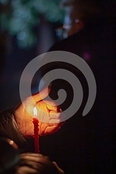 A woman holds a candle in her hand, covering the flame from the wind with her palm, in memory of the dead, killed, dead, deceased