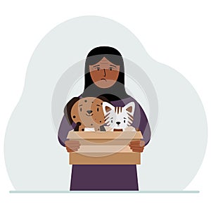 A woman holds a cardboard box with a cat and a dog. The concept of rescue, help and care for pets.