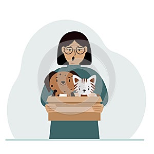 A woman holds a cardboard box with a cat and a dog. The concept of rescue, help and care for pets.