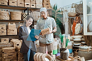 woman holds the clipboard and the man holds the wicker box while checking items