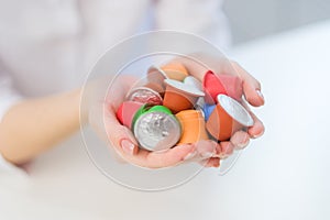 A woman holds coffee capulas in her hands and prepares espresso in a capsule coffee machine. White background. A bright