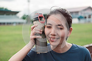 woman holds a cold water bottle against her cheek to cool down