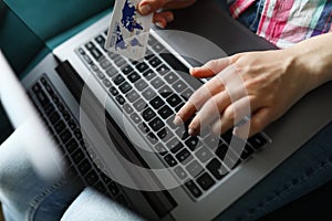 Woman holds credit card and types on laptop keyboard