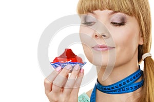 Woman holds cupcake trying to resist temptation