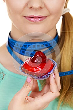 Woman holds cupcake trying to resist temptation