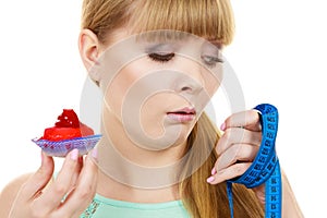 Woman holds cupcake trying to resist temptation