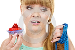 Woman holds cupcake trying to resist temptation