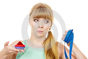 Woman holds cupcake trying to resist temptation