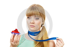 Woman holds cupcake trying to resist temptation