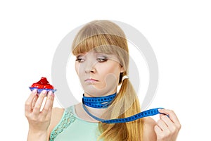 Woman holds cupcake trying to resist temptation