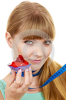 Woman holds cupcake trying to resist temptation