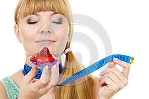 Woman holds cupcake trying to resist temptation